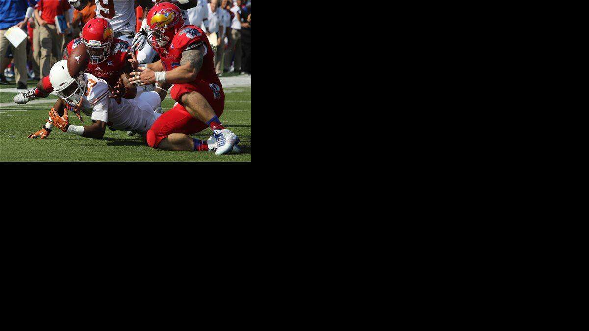 
Texas’ Armanti Foreman fumbled the ball in the first quarter Saturday as he was hit by Kansas’ Isaiah Johnson, back, and T.J. Semke in Lawrence.
