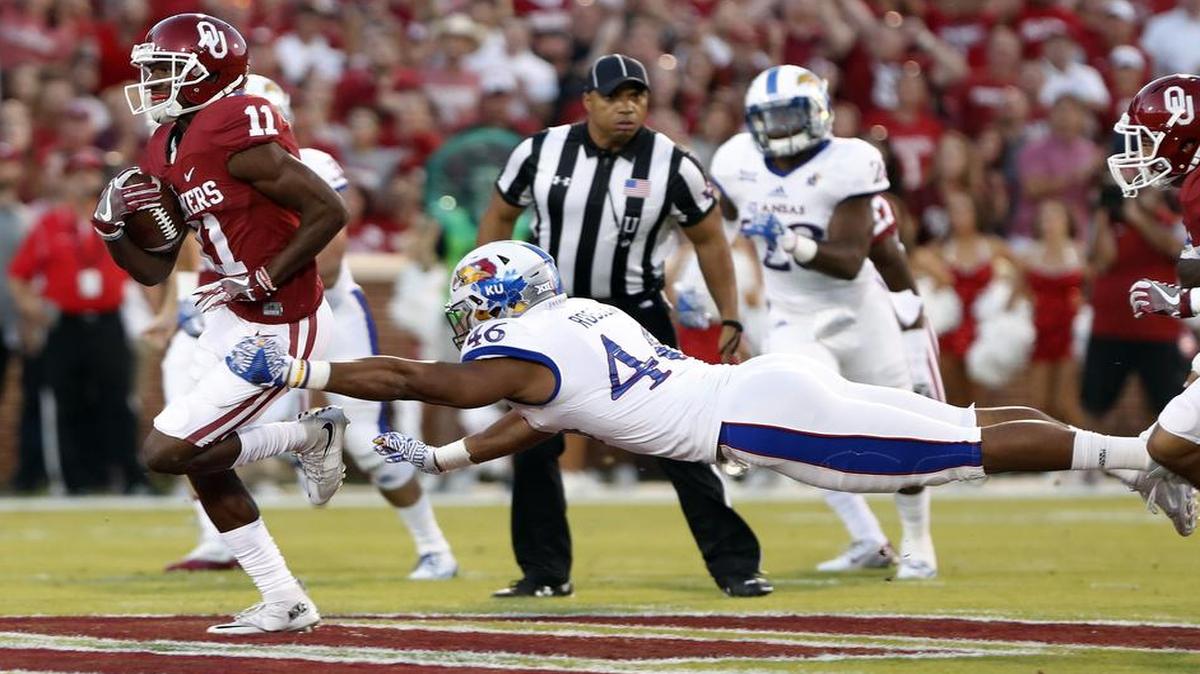 Oklahoma wide receiver Dede Westbrook (left) ran for a touchdown as Kansas defensive end Cameron Rosser missed a tackle during the first half of Saturday night’s game in Norman, Okla.