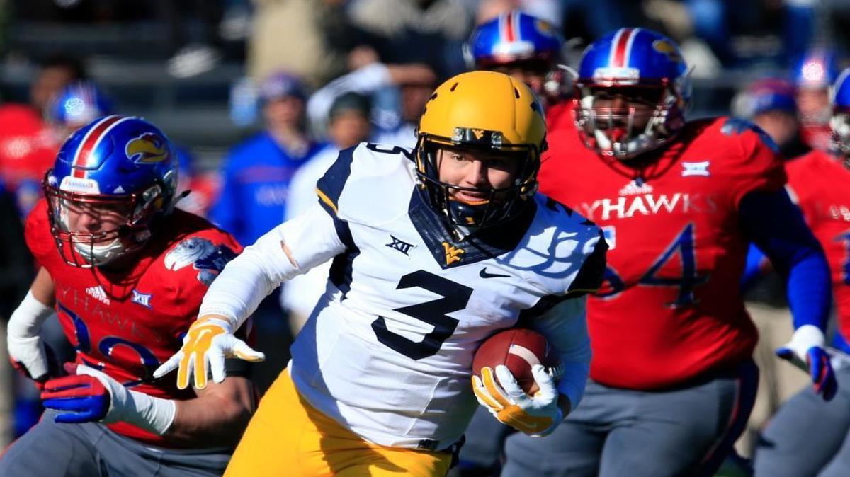 West Virginia quarterback Skyler Howard runs past Kansas linebacker Joe Dineen Jr. (left) and defensive tackle Jacky Dezir for a 42-yard gain during Saturday’s Big 12 football game in Lawrence.