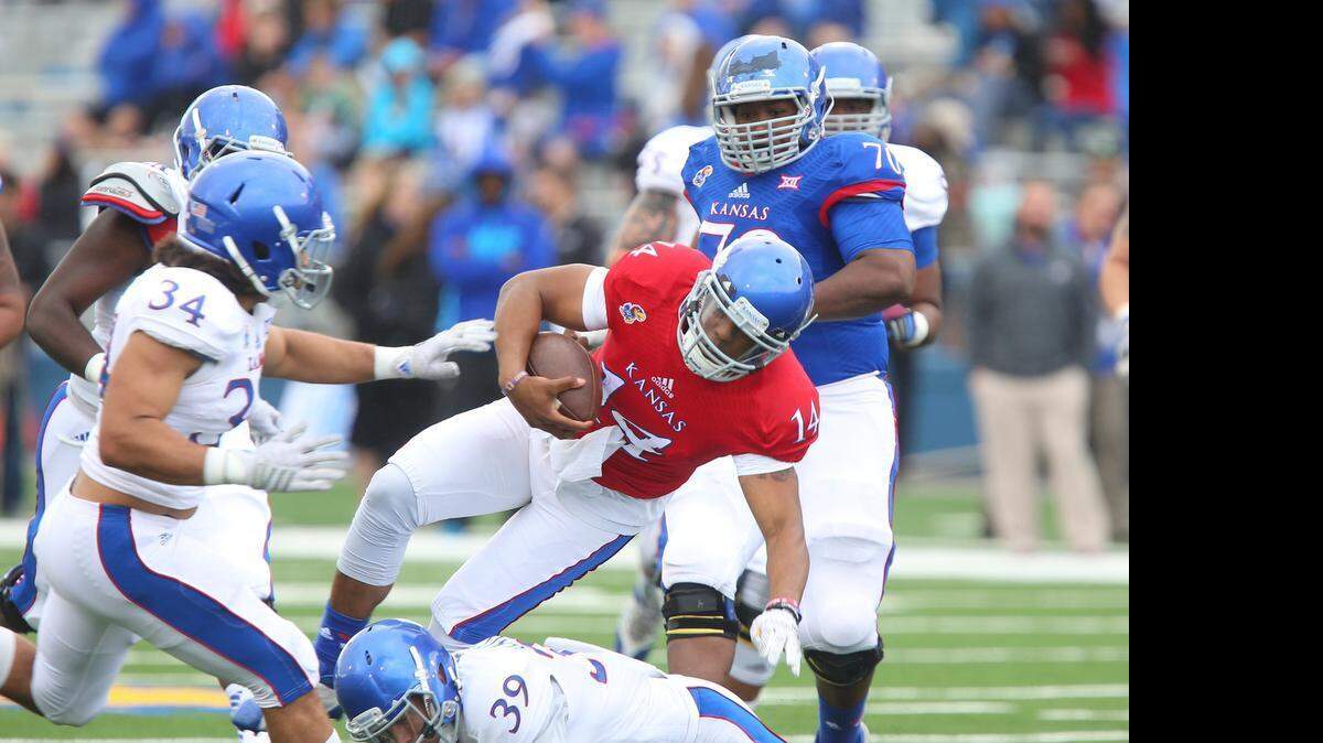 
Blue Team quarterback Michael Cummings (14) was taken out at the knees by White Team safety Michael Glatczak (39) on a quarterback run during the Kansas Jayhawks’ spring football game Saturday at Memorial Stadium in Lawrence. Cummings left the game with a knee injury.
