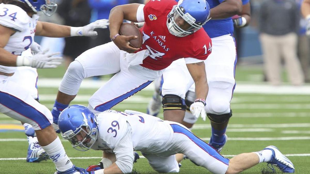 
KU quarterback Michael Cummings was tackled at the knees by safety Michael Glatczak during Kansas’ spring football game April 25.
