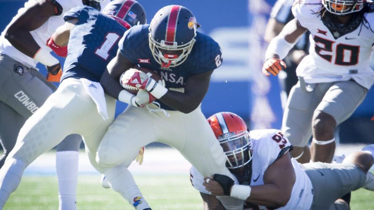 KU running back Taylor Martin (center) tried to pull his leg free from the grasp of Oklahoma State’s Vili Leveni in the first quarter of the Oct. 22 game in Lawrence. The Jayhawks ran for 228 yards against the Cowboys.