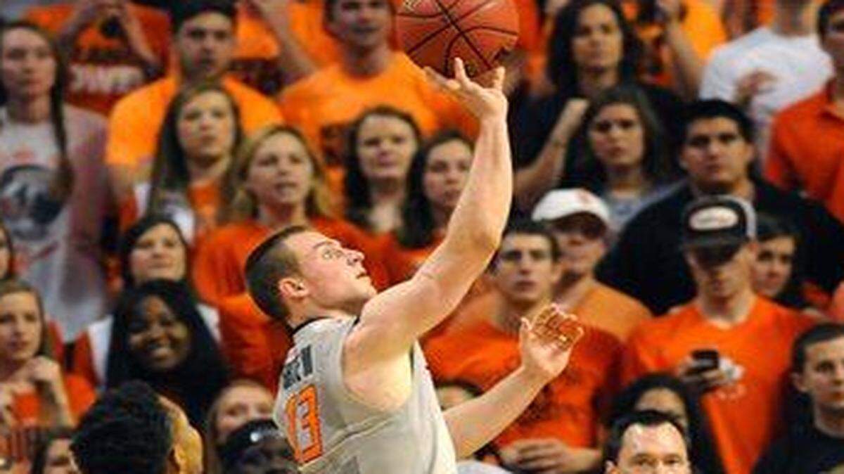 
Oklahoma State guard Phil Forte, who scored 13 points despite not feeling well, drove past KU’s Perry Ellis (left) and Devonte’ Graham in Saturday’s game.
