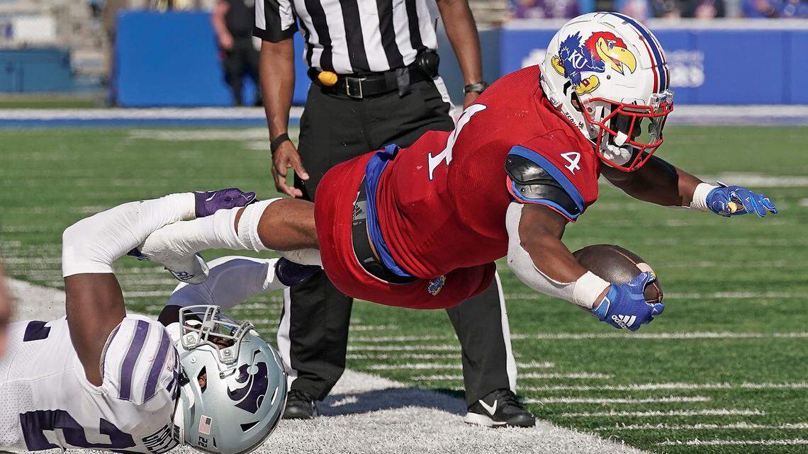 Kansas running back Devin Neal (right) is tackled by a Kansas State player during the second half Saturday, Nov. 6, 2021, in Lawrence,