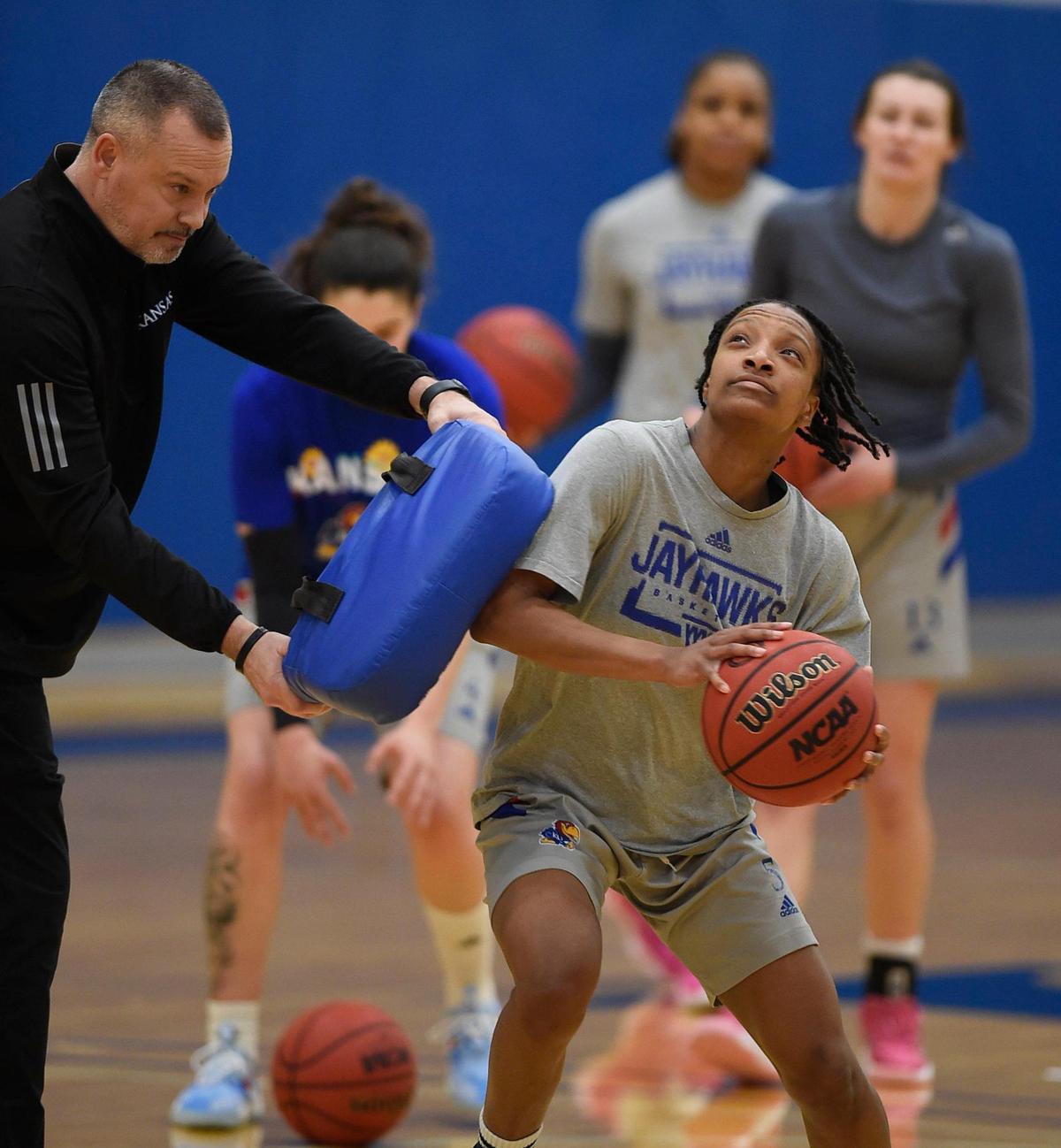 KU women’s basketball coach Brandon Schneider, left, has led the Jayhawks to a 19-5 record this season. They are currently in third position in the Big 12 standings with a league record of 10-4. Schneider leaned on senior guard Aniya Thomas during practice on Tuesday afternoon.