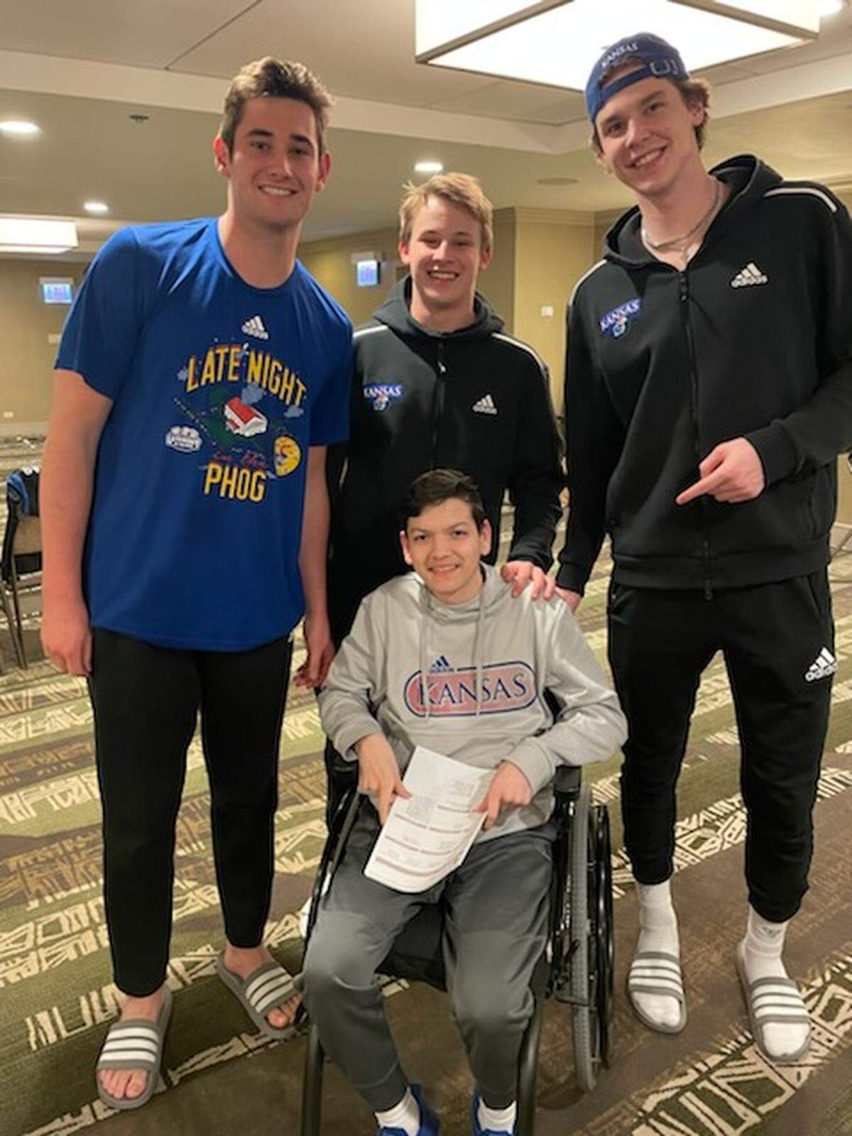 JP Bemberger of Lenexa, Kansas, front, poses for a photo with Kansas basketball players Dillon Wilhite, Charlie McCarthy and Zach Clemence during a team film session ahead of the Elite Eight in Chicago.