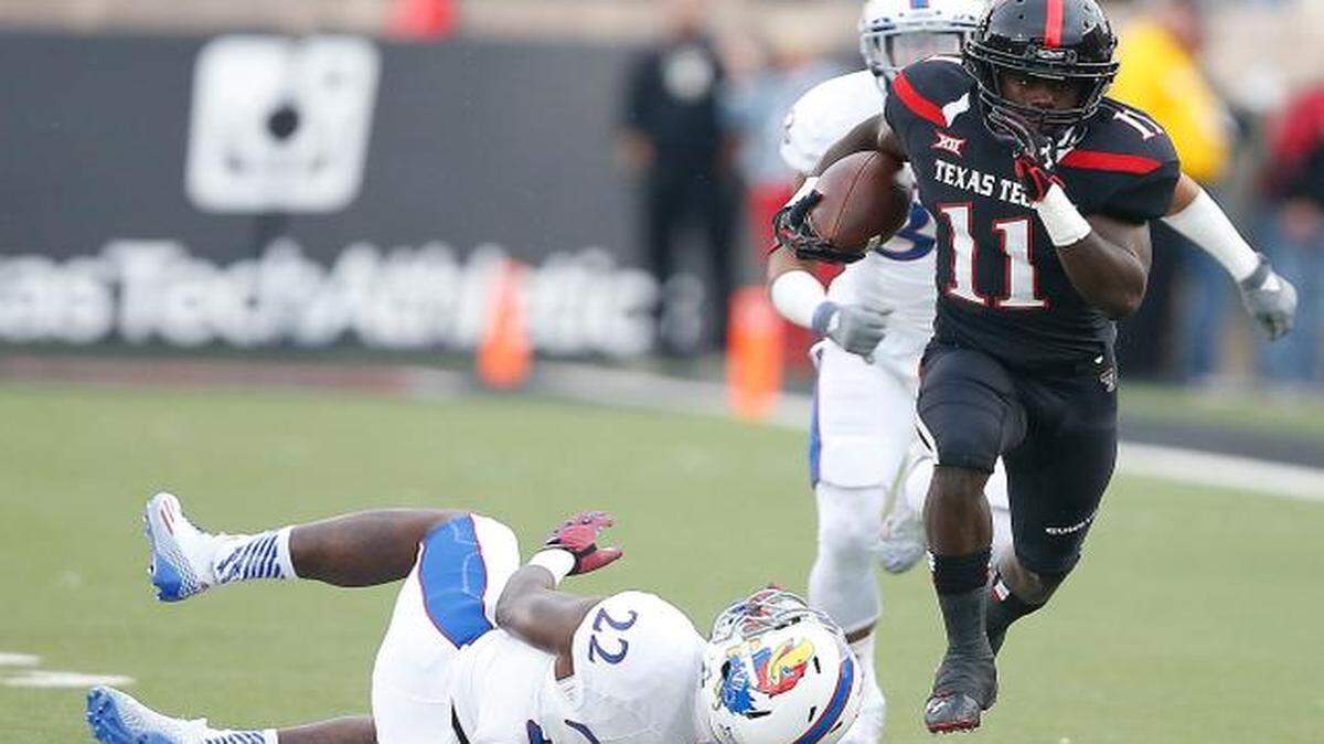 
Texas Tech’s Jakeem Grant got past Kansas’ Greg Allen (22) and Cassius Sendish (33) in the first half Saturday in Lubbock, Texas.
