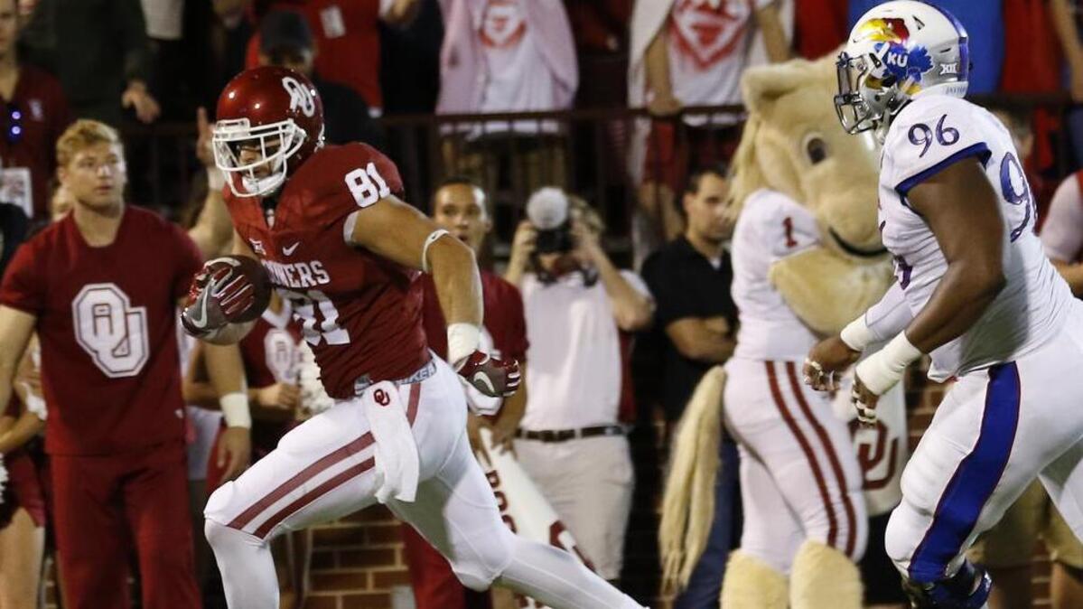 Oklahoma wide receiver Mark Andrews (81) runs for a touchdown ahead of Kansas defensive tackle Daniel Wise (96) during the first half of an NCAA college football game in Norman, Okla., Saturday, Oct. 29, 2016.