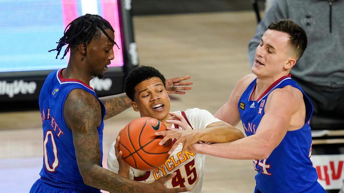 Iowa State guard Rasir Bolton, center, looks to pass between Kansas guard Marcus Garrett, left, and forward Mitch Lightfoot, right, during the second half of a college basketball game, Saturday, Feb. 13, 2021, in Ames, Iowa. Kansas won 64-50.