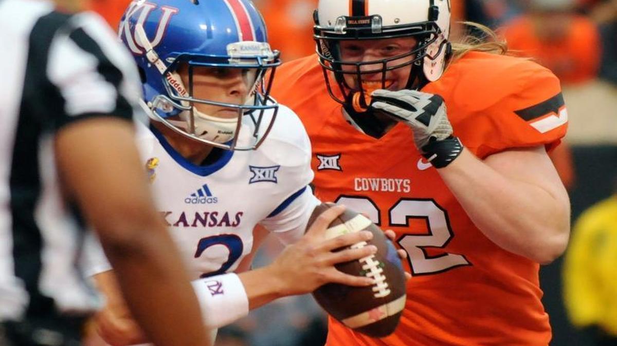 Oklahoma State defensive tackle Tyler Ferguson (right) sacked Kansas quarterback Ryan Willis for a 10-yard loss in the fourth quarter Saturday in Stillwater, Okla. Willis had 191 yards passing in the Jayhawks’ 58-10 loss.