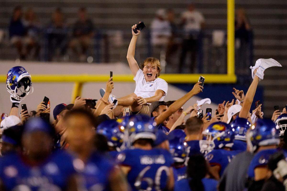 A fan celebrates on the field after an NCAA college football game between Kansas and South Dakota Friday, Sept. 3, 2021, in Lawrence, Kan. Kansas won 17-14.