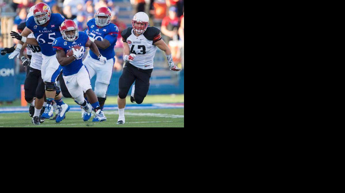 
Kansas Jayhawks running back De'Andre Mann (23) breaks through a hole in the lines of scrimmage in the first quarter during the University of Kansas and Southeast Missouri State football game at Memorial Stadium on Saturday, September 6, 2014, in Lawrence, Kansas.
