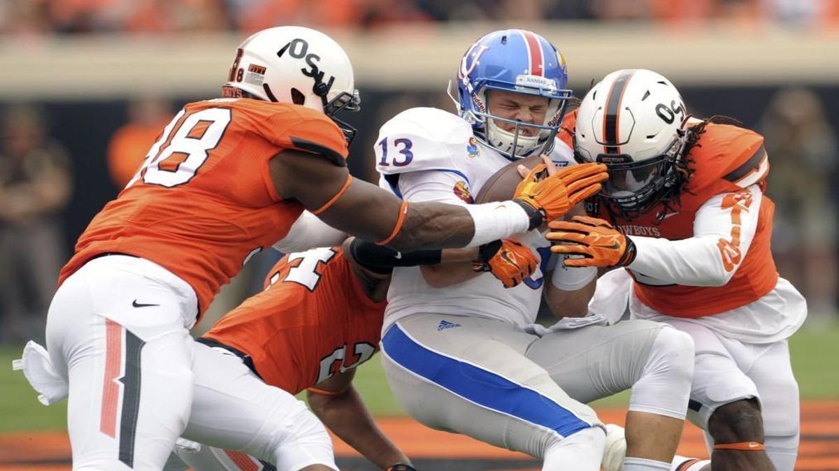 A trio of Oklahoma State defenders tackled Kansas quarterback Ryan Willis during a game last month.