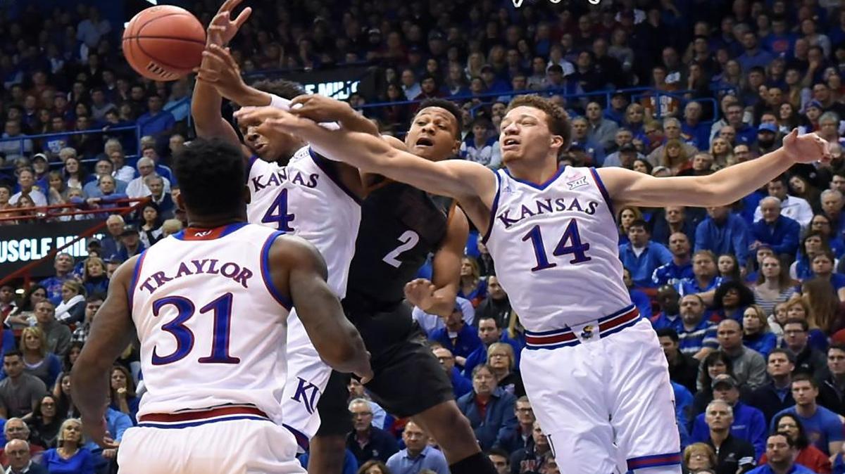 Kansas’ Devonte’ Graham and Brannen Greene (right) battled Texas’ Demarcus Holland for a rebound during the first half of Saturday’s game at Allen Fieldhouse. KU beat Texas 76-67.