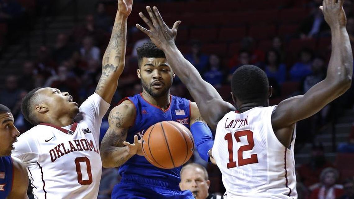 Kansas guard Frank Mason III, center, passes between Oklahoma guard Darrion Strong-Moore (0) and forward Khadeem Lattin (12) during the first half of an NCAA college basketball game in Norman, Okla., Tuesday, Jan. 10, 2017.