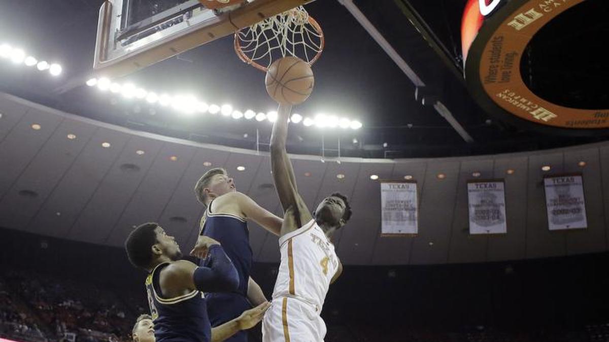 Texas forward Mohamed Bamba (4) scored over Michigan defenders Jon Teske (15) and Zavier Simpson (3) during the second half of an game on Tuesday, Dec. 12, 2017, in Austin, Texas. Michigan won 59-52. Bamba, a freshman, has blocked 47 shots in 11 games.