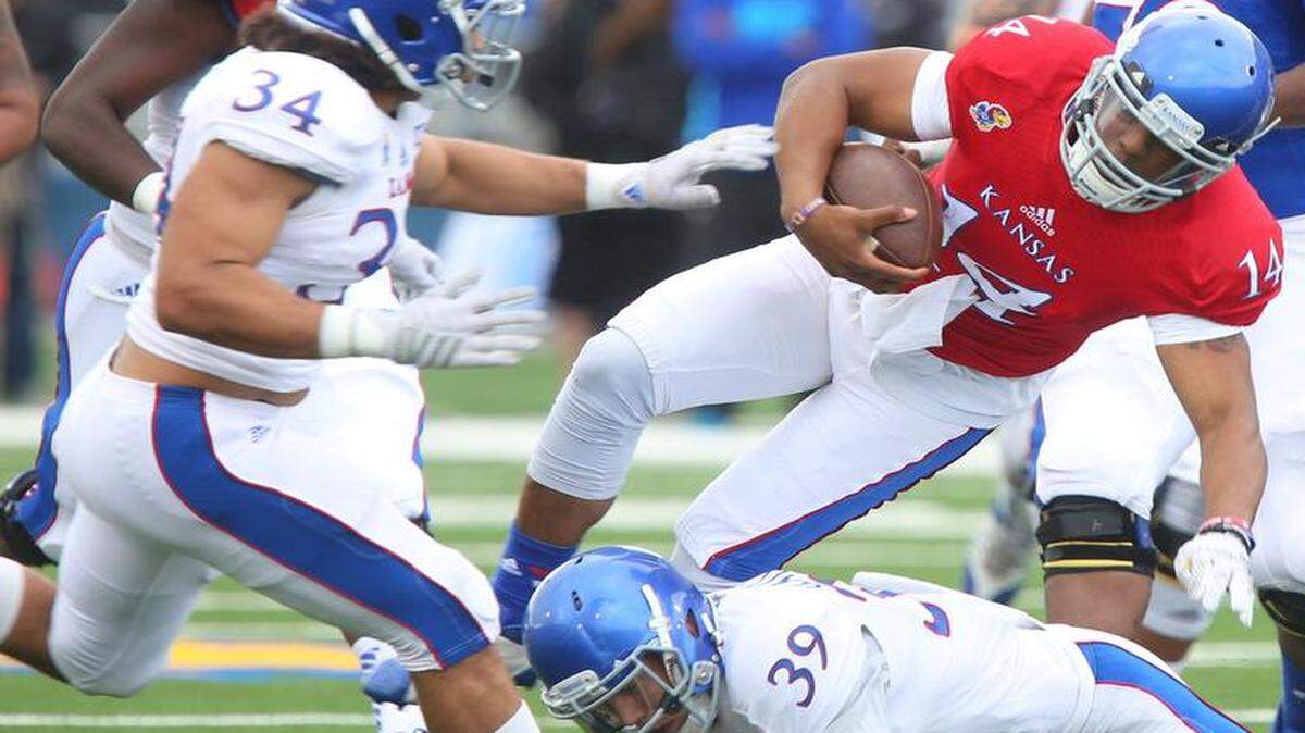 
Blue Team quarterback Michael Cummings (14) was taken out at the knees by White Team safety Michael Glatczak (39) on a quarterback run during the Kansas Jayhawks’ spring football game Saturday at Memorial Stadium in Lawrence. Cummings left the game with a knee injury.
