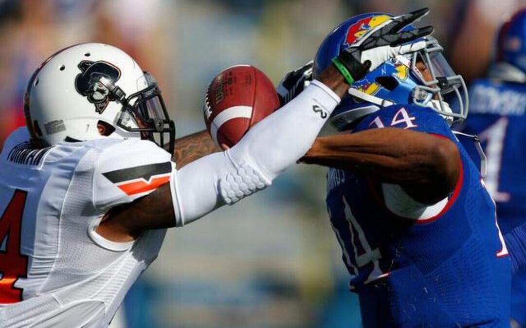 
Oklahoma State safety Dylan Harding (4) forced a fumble by Kansas quarterback Michael Cummings (14) in the first half Saturday in Lawrence.
