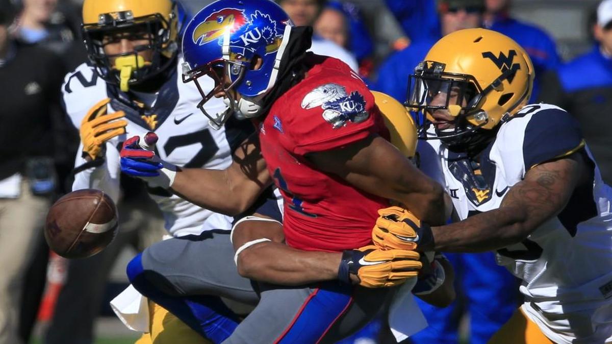 Kansas wide receiver Tre’ Parmalee fumbles when hit by West Virginia cornerback Terrell Chestnut (left) and safety Dravon Askew-Henry during Saturday’s game. West Virginia safety Jarrod Harper (22) recovered the ball on the play.