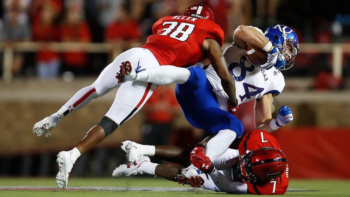 Texas Tech's Kisean Allen (38) and Jah'Shawn Johnson (7) tackle Kansas' Ben Johnson (84) during an NCAA college football game Thursday, Sept. 29, 2016, in Lubbock, Texas.