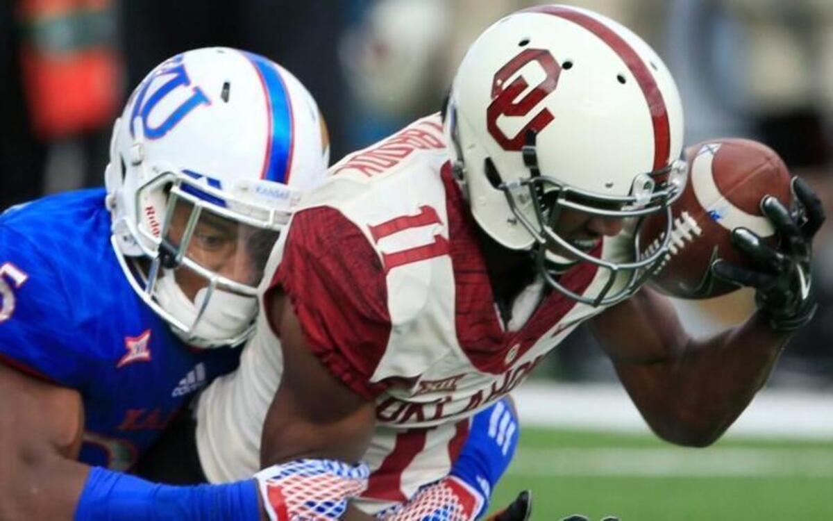 Oklahoma wide receiver Dede Westbrook (11) caught a pass for a first down while being tackled by Kansas cornerback Marnez Ogletree (25) in the first half Saturday in Lawrence. The No. 13 Sooners went on to beat the Jayhawks 62-7.