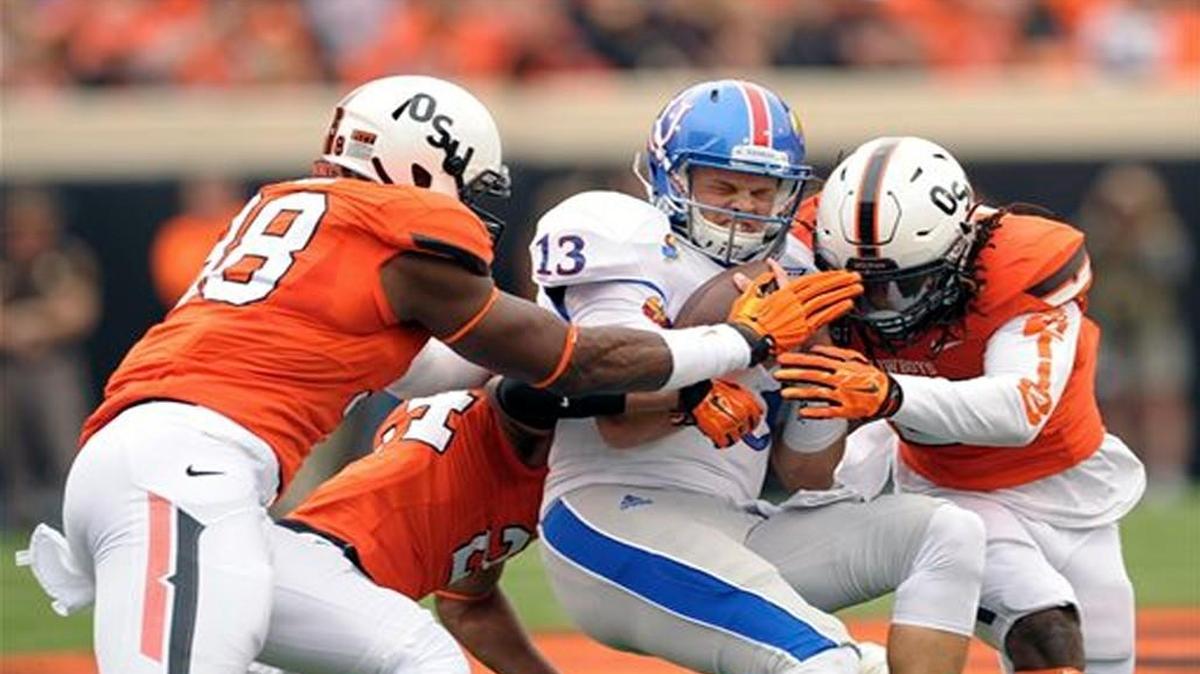 Oklahoma State’s Emmanuel Ogbah (left), Miketavius Jones and Jordan Burton (right) tackled Kansas quarterback Ryan Willis in Saturday’s game.