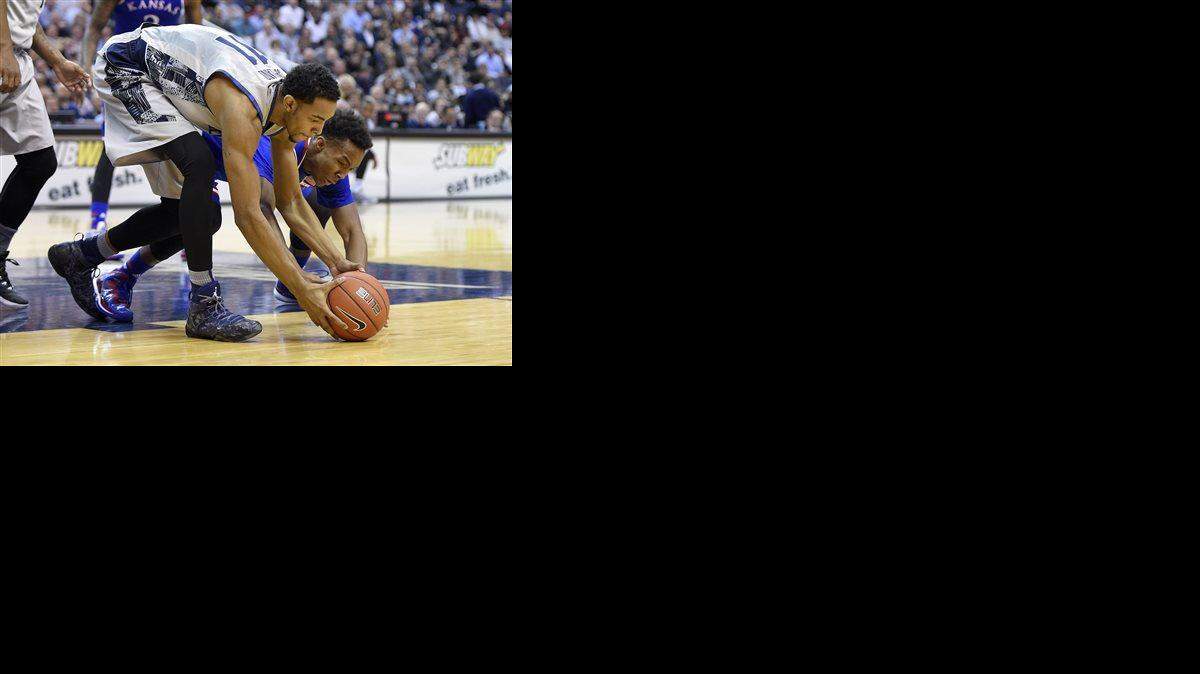 Kansas guard Devonte Graham, back, fights for a loose ball against Georgetown forward Isaac Copeland, front, during the first half of an NCAA college basketball game, Wednesday, Dec. 10, 2014, in Washington.