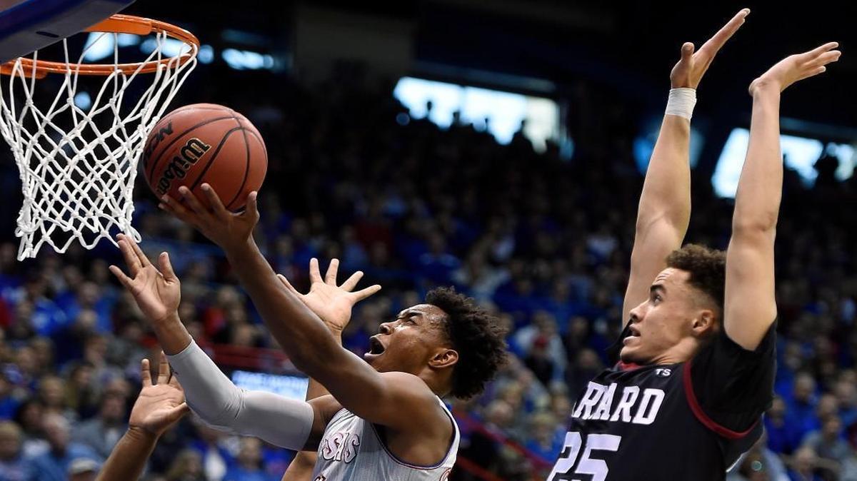 Kansas’ Devonte’ Graham drove between Harvard defenders Zena Edosomwan (4) and Corey Johnson in the first half of Saturday’s game at Allen Fieldhouse in Lawrence.