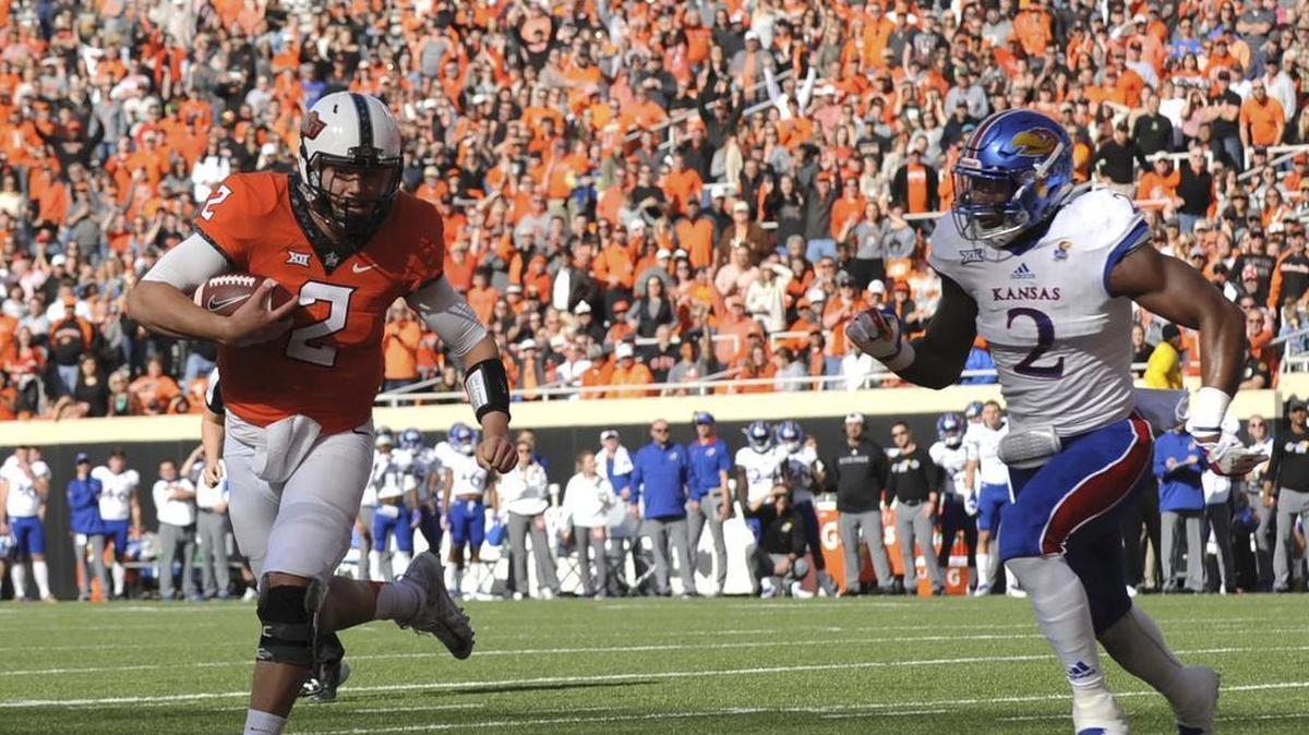 Kansas defensive end Dorance Armstrong Jr., right, chases after Oklahoma State quarterback Mason Rudolph as he scores a touchdown in the first half of the Cowboys’ victory Saturday in Stillwater, Okla.