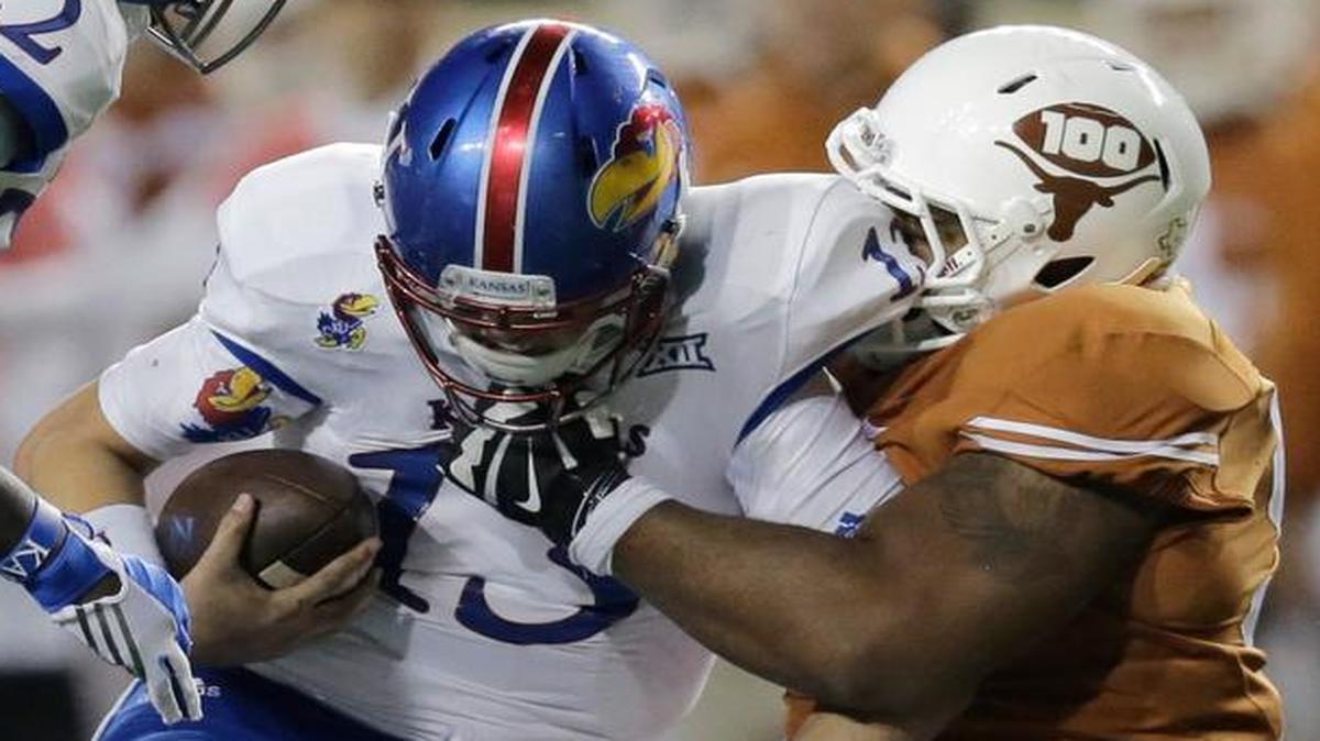 Kansas quarterback Ryan Willis (13) was sacked by Texas defensive tackle Desmond Jackson (right) in the second half of the Longhorns’ 59-20 win over the Jayhawks on Saturday night in Austin, Texas.
