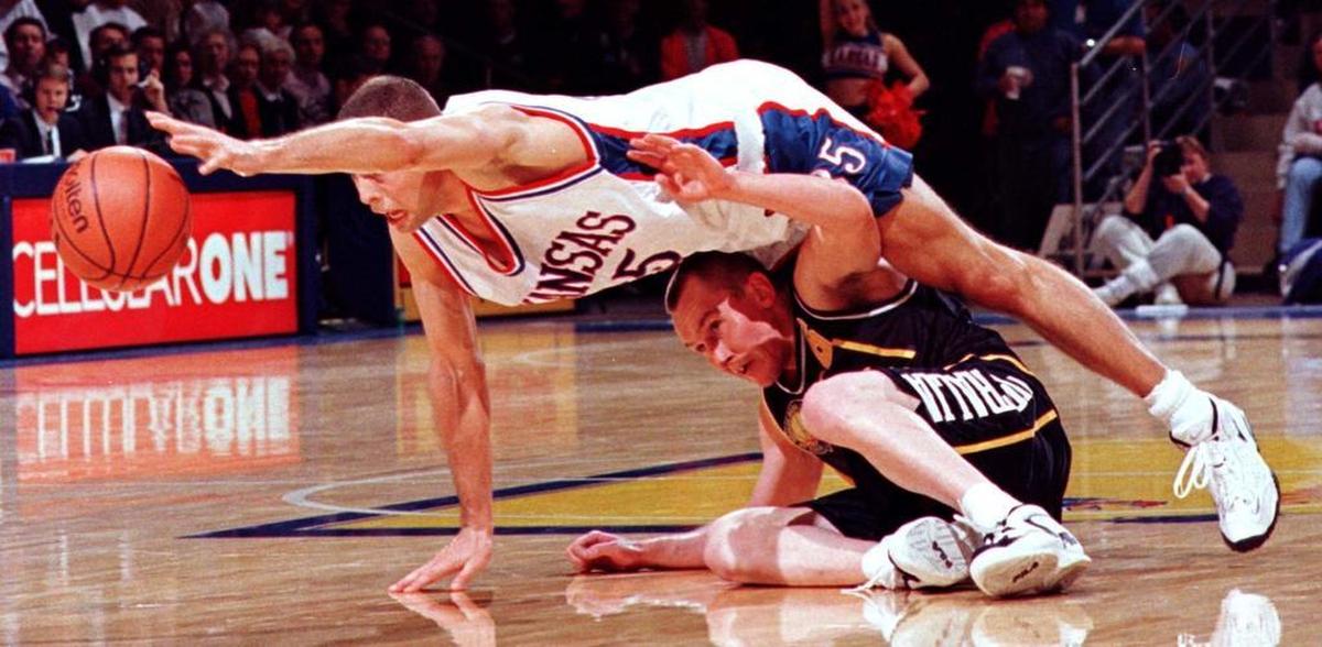 Kansas guard Jerod Haase dives over a player during a 1996 preseason game at Allen Fieldhouse, the type of play that led to the name of Haase’s book, “Floor Burns.”