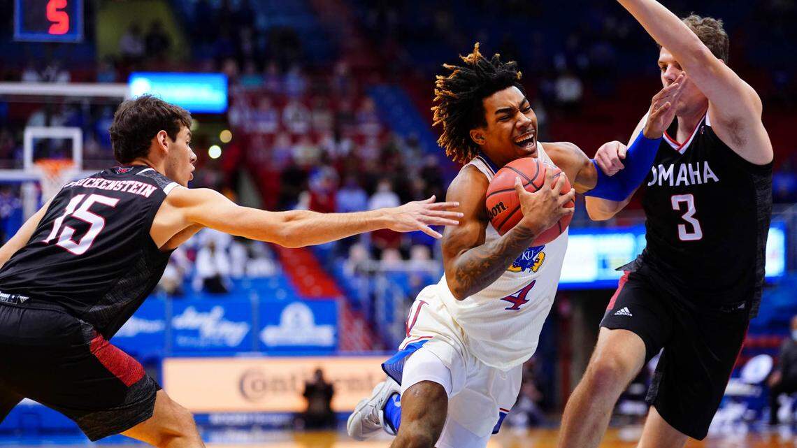 Kansas guard Latrell Jossell (4) gets through Omaha guard Grant Frickenstein (15) and Omaha guard Kyle Luedtke (3) for a bucket during the second half on Friday, Dec. 11, 2020 at Allen Fieldhouse.