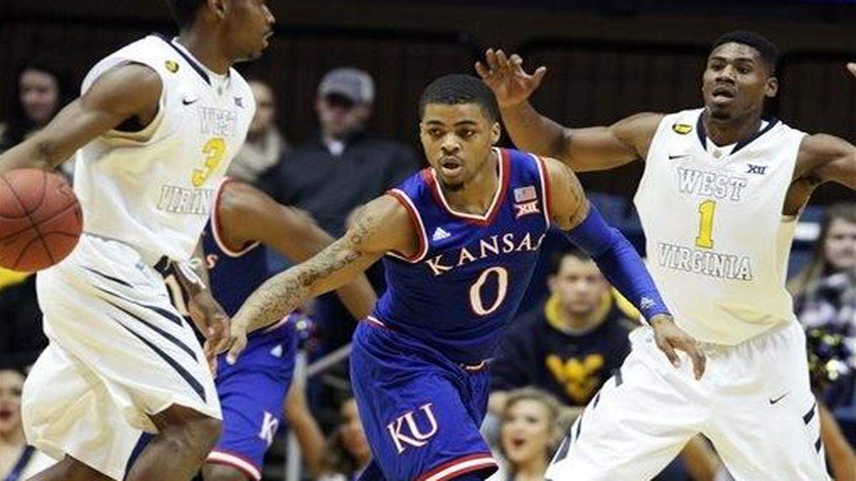 
West Virginia guard Juwan Staten (3) drives up court while being guard by Kansas guard Frank Mason III (0) during Monday’s game in Morgantown.

