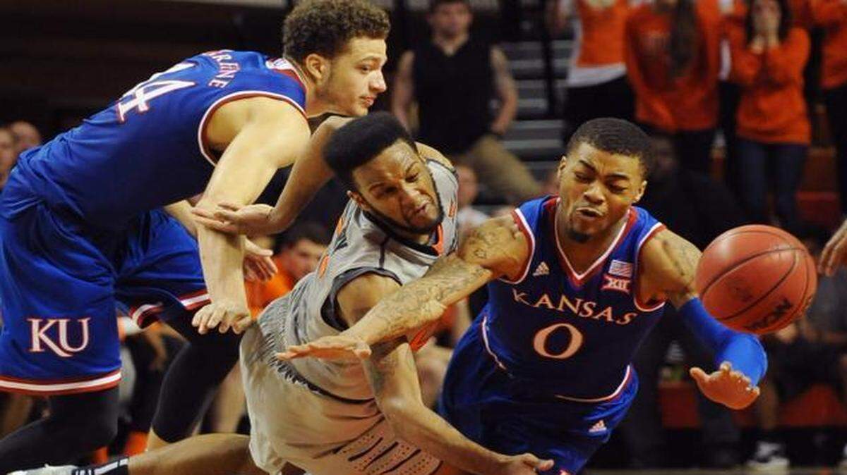 
Kansas guard Brannen Greene (left) Oklahoma State guard Anthony Hickey (center) and Kansas guard Frank Mason III fell while chasing a loose ball during the final minutes on Saturday in Stillwater, Okla. Hickey scored 15 points in the 67-62 win over Kansas.
