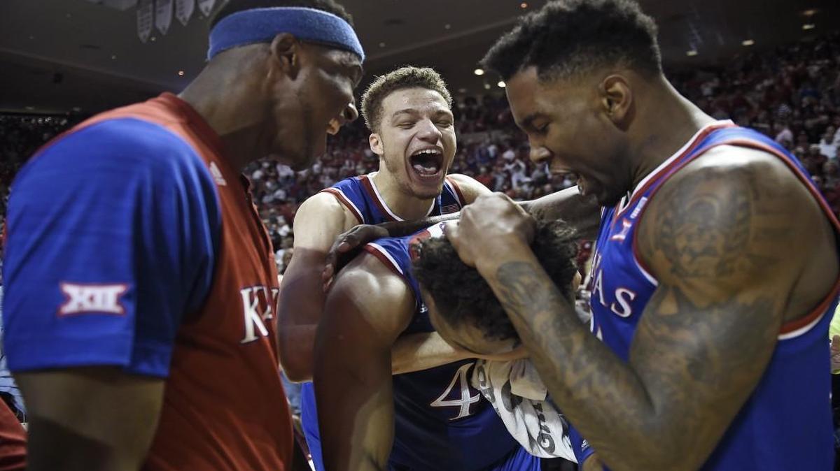 KU’s Devonte’ Graham was greeted enthusiastically by teammates Carlton Bragg (from left), Brannen Greene and Jamari Traylor after the Jayhawks beat Oklahoma on Saturday.