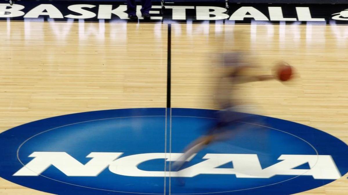 In this March 14, 2012, file photo made with a long exposure, a player runs across the NCAA logo at midcourt during practice in Pittsburgh before an NCAA tournament college basketball game.
