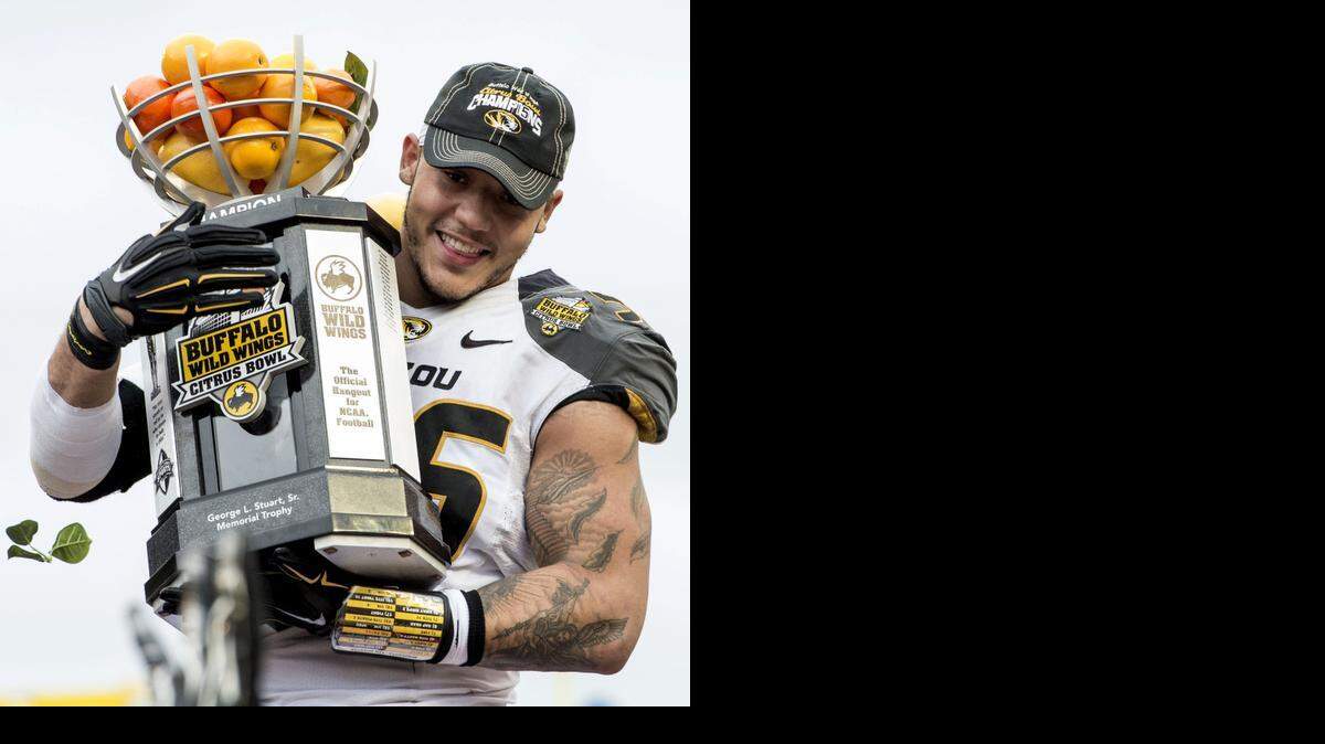 
Missouri Tigers defensive lineman Shane Ray (56) carries the Buffalo Wild Wings Citrus Bowl trophy off of the stage after the University of Missouri beat the University of Minnesota 33-17 in the Citrus Bowl football game on Thursday, January 1, 2015, near Orlando, Florida.
