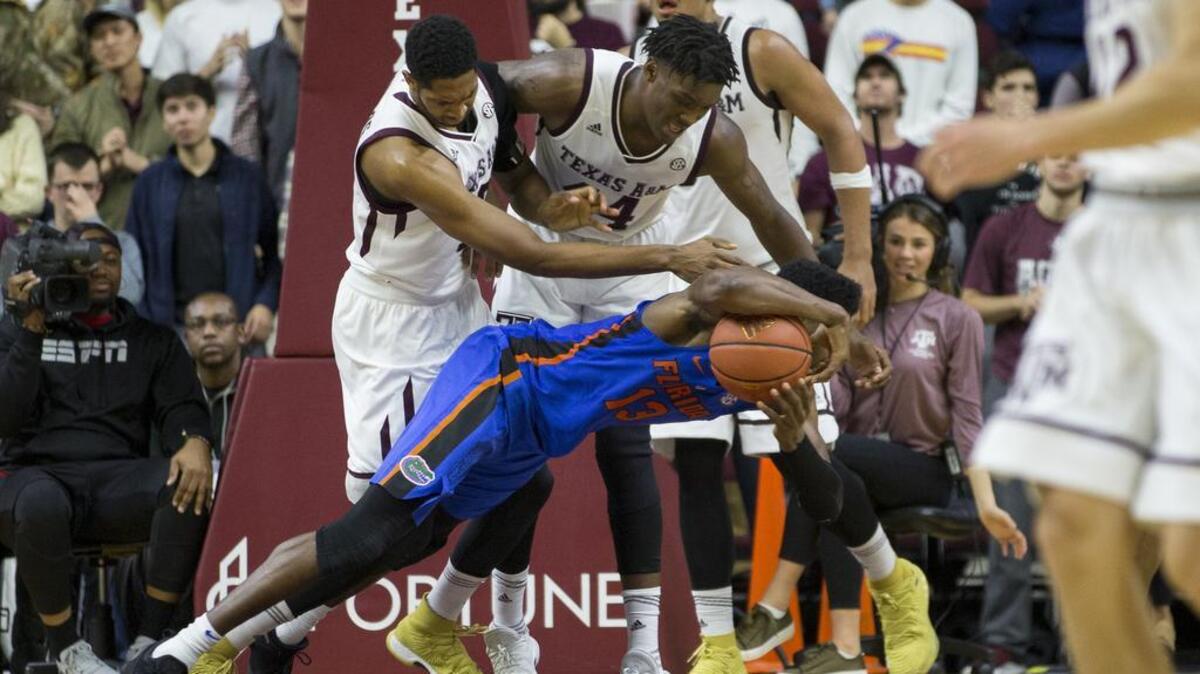 Florida forward Kevarrius Hayes (13) dives for a loose ball against Texas A&M center Tonny Trocha-Morelos (10) and forward Robert Williams (44) during the second half of an NCAA college basketball game Tuesday, Jan. 2, 2018, in College Station, Texas. Florida won, 83-66.