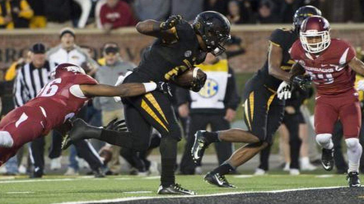 
Missouri Tigers running back Marcus Murphy (6) dragged Arkansas Razorbacks safety Rohan Gaines (26) across the goal line to score the winning touchdown in the fourth quarter during Missouri’s 21-14 win over Arkansas, giving the Tigers their second consecutive SEC East Division Championship.


