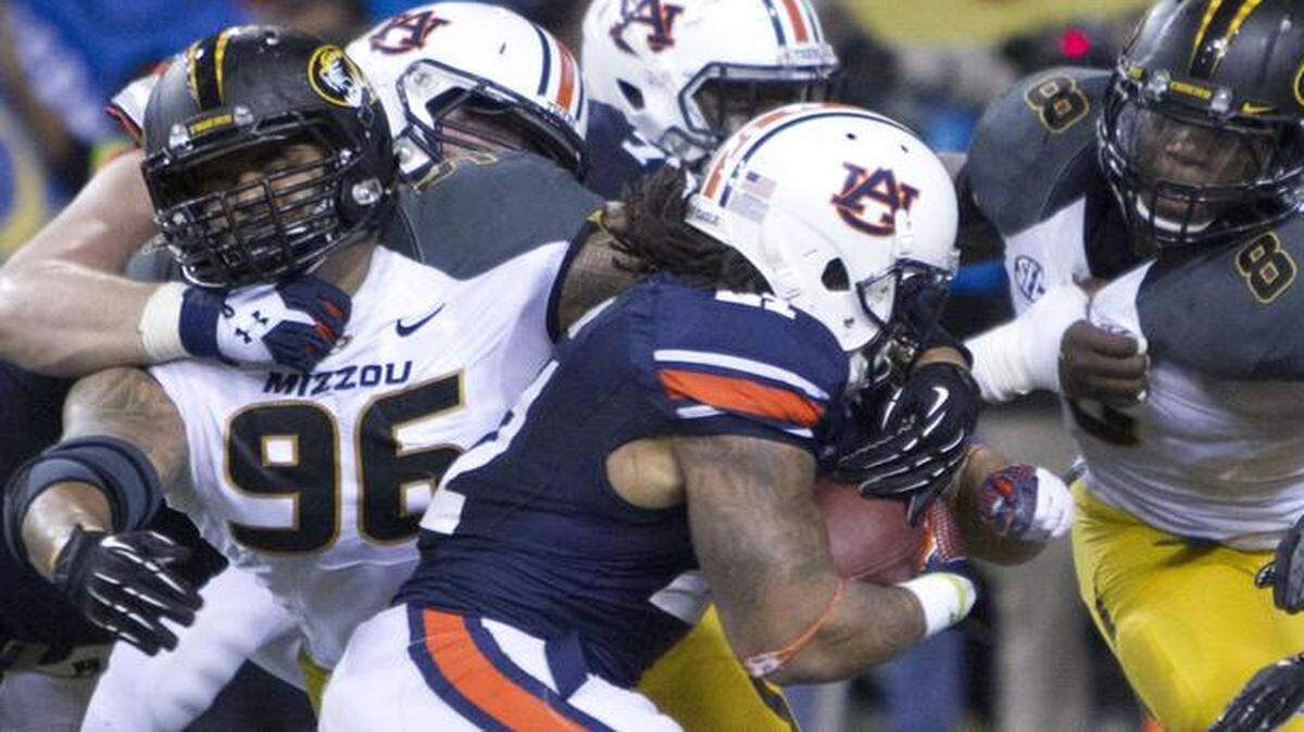 
Missouri Tigers defensive lineman Lucas Vincent (left) and linebacker Donovan Bonner (right) tried to fight off their blocks to tackle Auburn Tigers running back Tre Mason in last season’s SEC championship football game.
