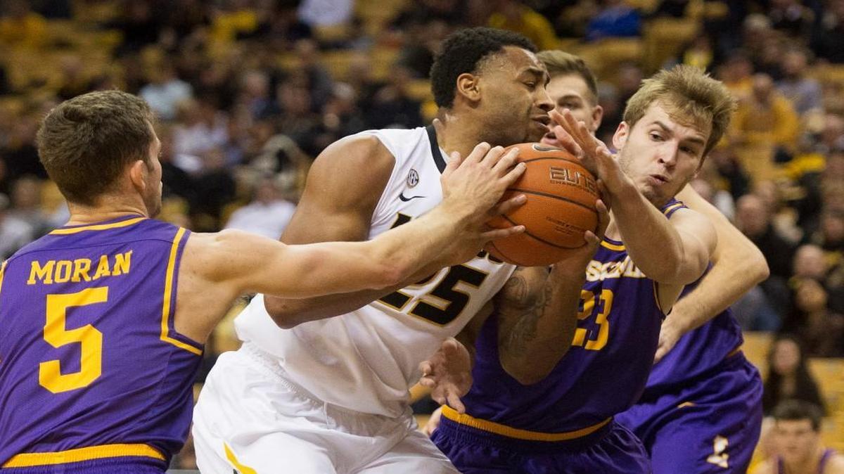 Missouri’s Russell Woods (center) fights his way between Lipscomb’s Nathan Moran (left) and Aaron Korn as he drives toward the basket during the first half Thursday in Columbia, Mo.