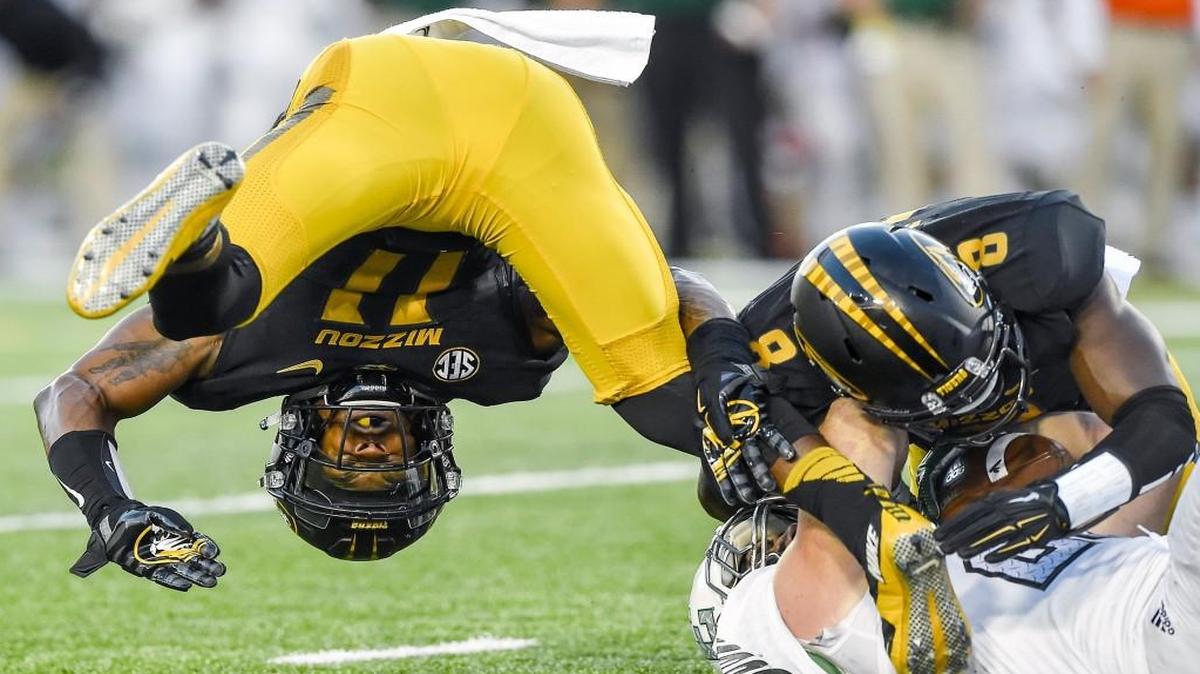 Missouri defensive back Aarion Penton (11) flipped as he and Tigers safety Thomas Wilson (8) tackled Eastern Michigan running back Ian Eriksen (25) on Saturday night in Columbia. The Tigers beat the Eagles 61-21.