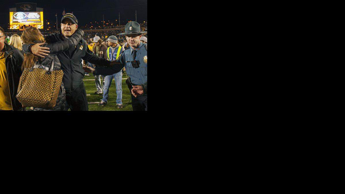 Missouri head coach Gary Pinkel, center, is hugged by fans after they defeated Arkansas 21-14 in an NCAA college football game Friday, Nov. 28, 2014, in Columbia, Mo.