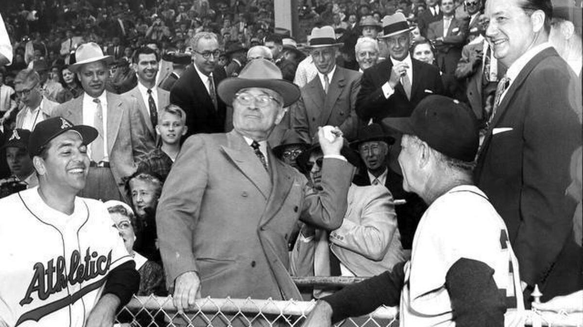 President Truman threw out the first pitch from the Kansas City Athletics’ dugout before their 1955 debut at Municipal Stadium on April 12. At left is A’s manager Lou Boudreau; at right in the foreground is Detroit Tigers manager Bucky Harris. Also pictured are A’s owner Arnold Johnson and former owner Connie Mack.