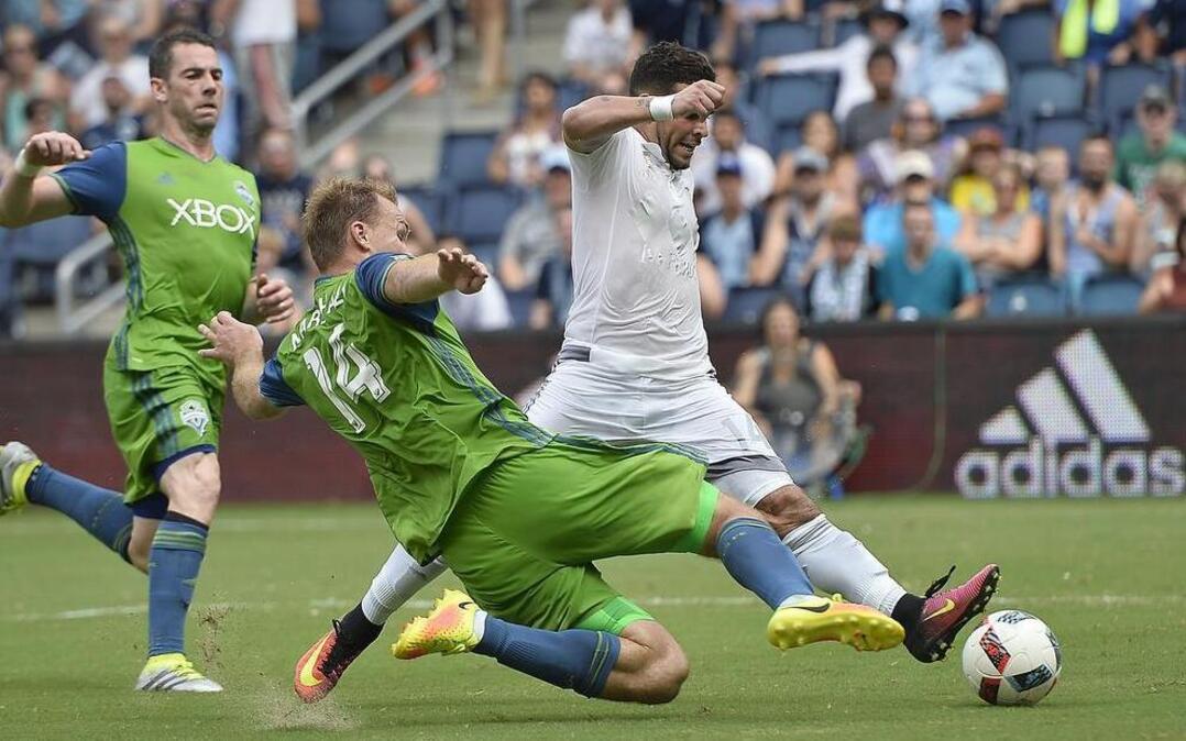 Sporting Kansas City hosted the Seattle Sounders FC at Children's Mercy Park Sunday, July 24, 2016. Not long after scoring his second goal of the game in the second half, Sporting KC's Dom Dwyer (right) attempted another shot as Seattle's Chad Marshall (14) tried to block it. Sporting KC defeated Seattle 3-0.