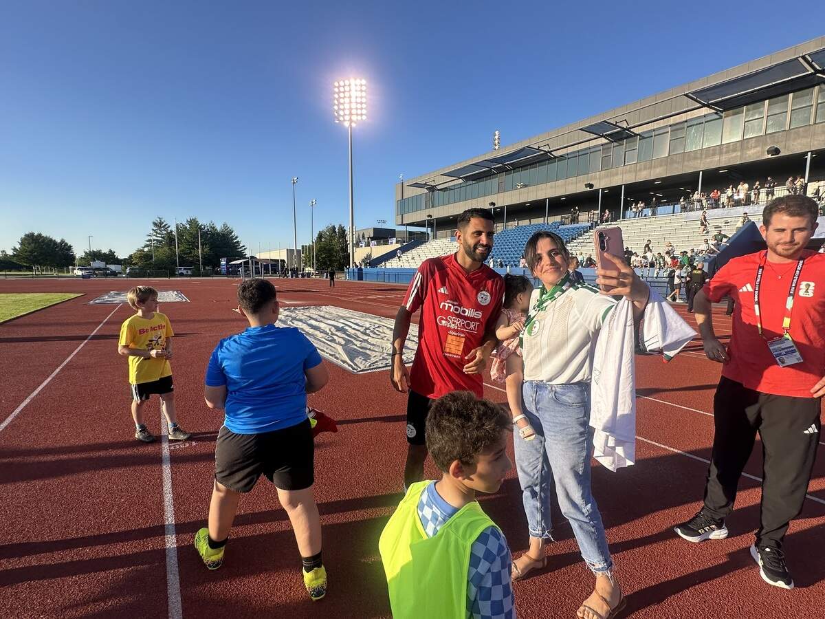 Algerian great Riyad Mahrez takes a photo with a fan at Rock Chalk Park during Algeria’s community World Cup practice in Lawrence on Thursday, June 11, 2026. Algerian players also connected with youth players during a kids camp.