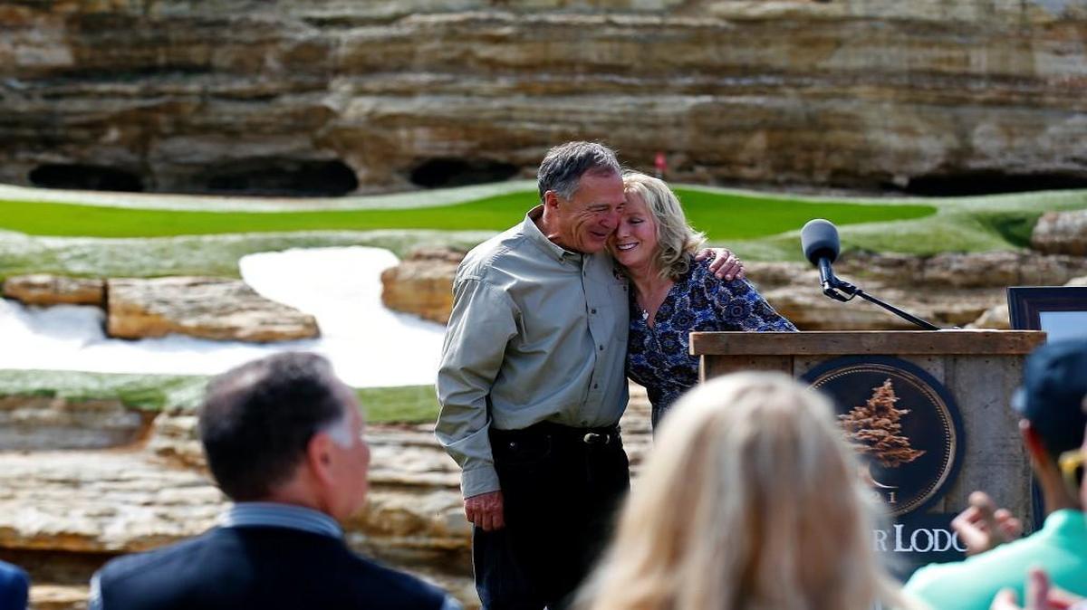 Bass Pro Shops founder and CEO Johnny Morris and Tracey Stewart hug during a press event for a new golf course designed by Tiger Woods, in Hollister, Mo., on April 18.