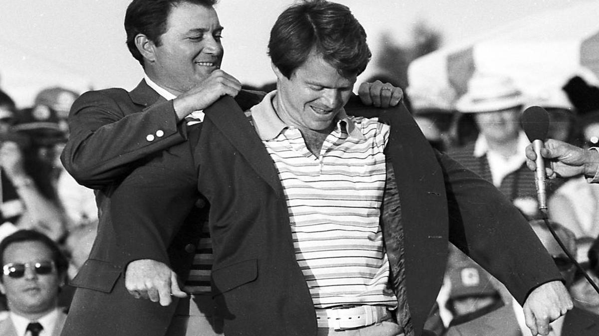 Tom Watson, 1977 winner of The Masters, receives the traditional green jacket from previous champion Ray Floyd.