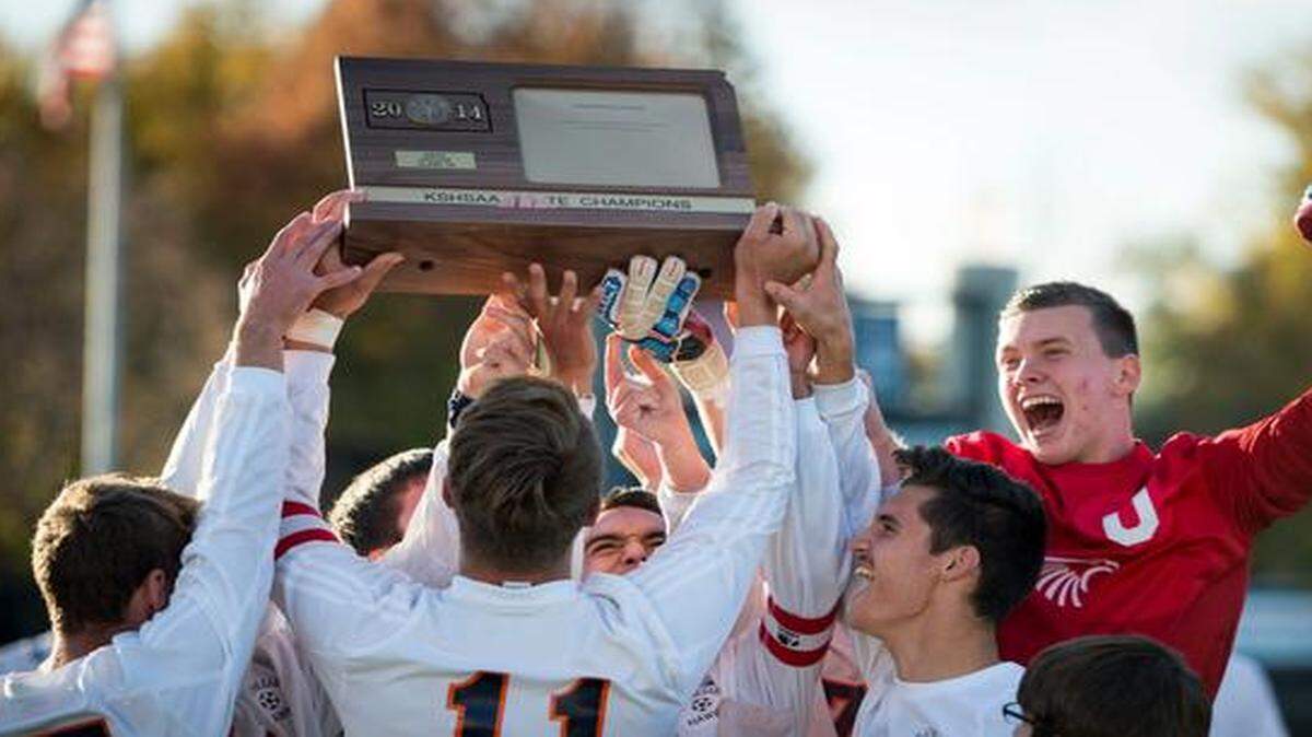 
Olathe East’s Brent Krull (17), Zac Marquess (11), Mark Vanlandingham (5) and goalkeeper Collin Shepard (0) hoisted the trophy after winning the Kansas Class 6A soccer championship game Saturday in Topeka. Olathe East beat Washburn Rural 2-1.
