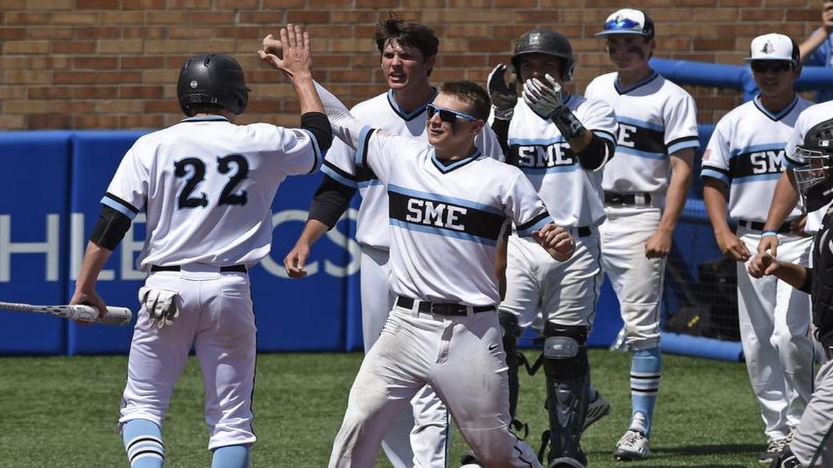 Shawnee Mission East’s Luke Anderson (left, No. 22) was congratulated by his teammates after scoring a run in the Class 6A championship game in Lawrence.